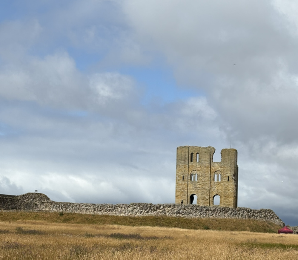 Scarborough Castle ruins — “Scarborough Castle ruins on a grassy hill, showing the tall stone keep and arched openings against a partly cloudy sky